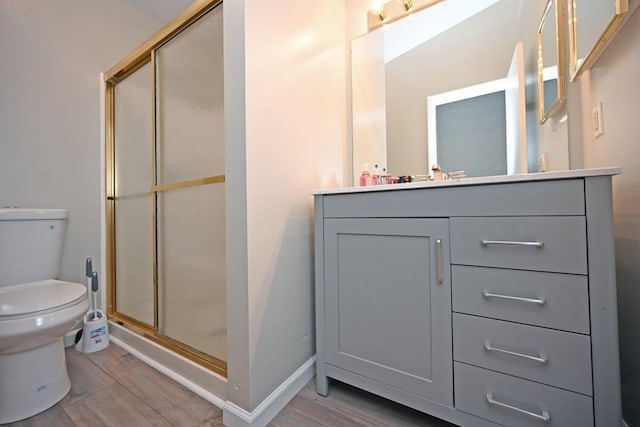 bathroom with toilet, a shower with door, vanity, and hardwood / wood-style flooring