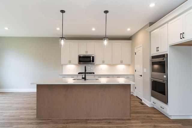 3850 Sherbourne Dr, Independence, KY 41051 - kitchen with stainless steel appliances, wood finished floors, decorative backsplash, a center island with sink, and baseboards