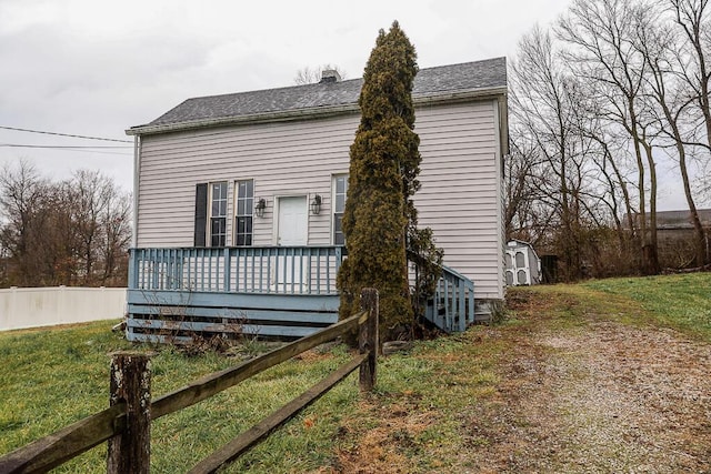 view of side of home featuring a shed, a deck, and a lawn