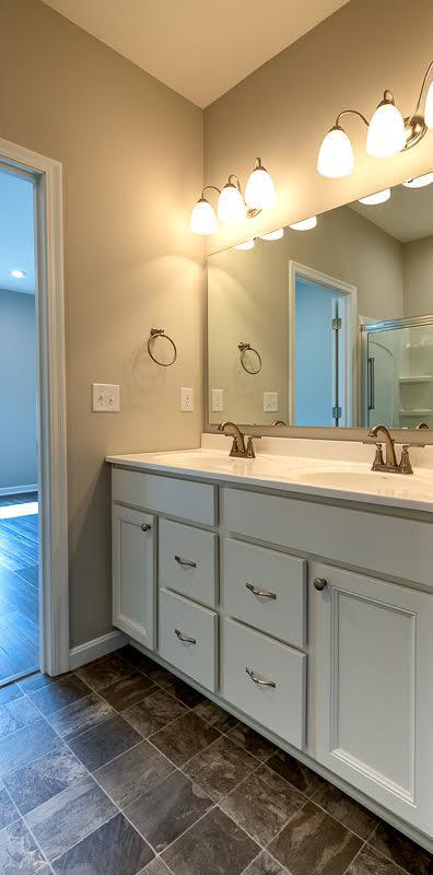 full bathroom featuring an enclosed shower, double vanity, baseboards, and a sink