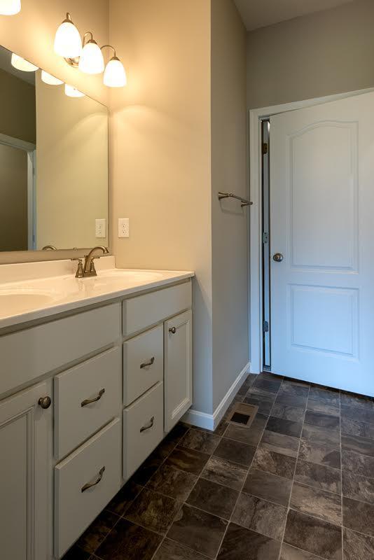 bathroom with double vanity, baseboards, stone finish flooring, and a sink