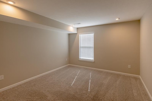 empty room featuring baseboards and light carpet