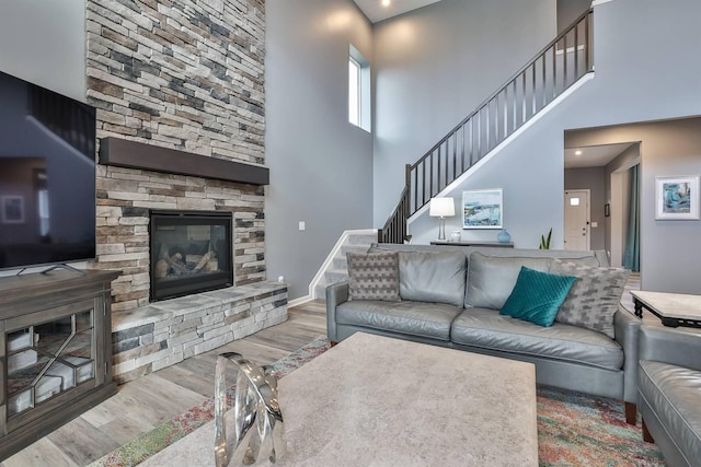 living room featuring light hardwood / wood-style flooring, a fireplace, and a towering ceiling