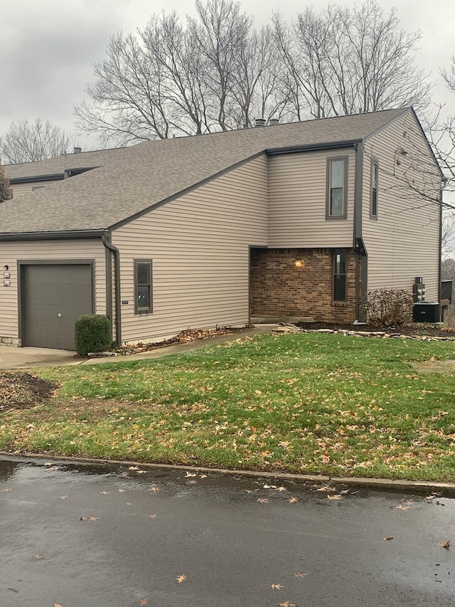 view of side of property featuring a yard, central air condition unit, and a garage