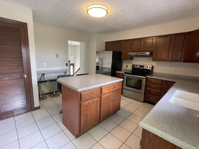 kitchen with a textured ceiling, a center island, stainless steel appliances, and sink