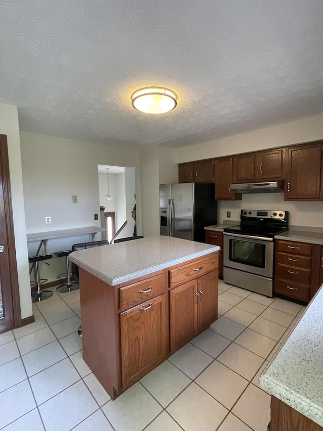 kitchen with light stone countertops, a center island, a textured ceiling, and appliances with stainless steel finishes