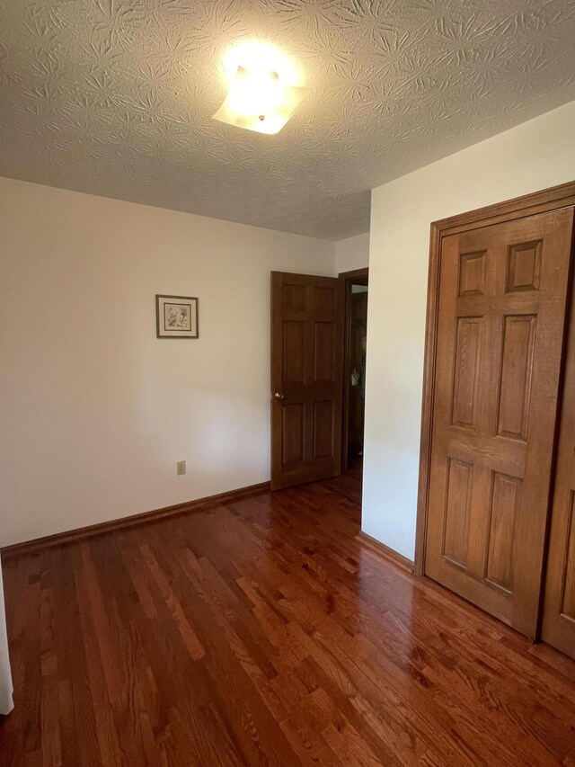 interior space with a textured ceiling and dark hardwood / wood-style flooring