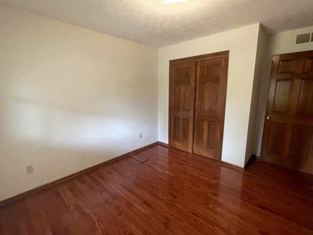 unfurnished bedroom with dark hardwood / wood-style flooring and a textured ceiling