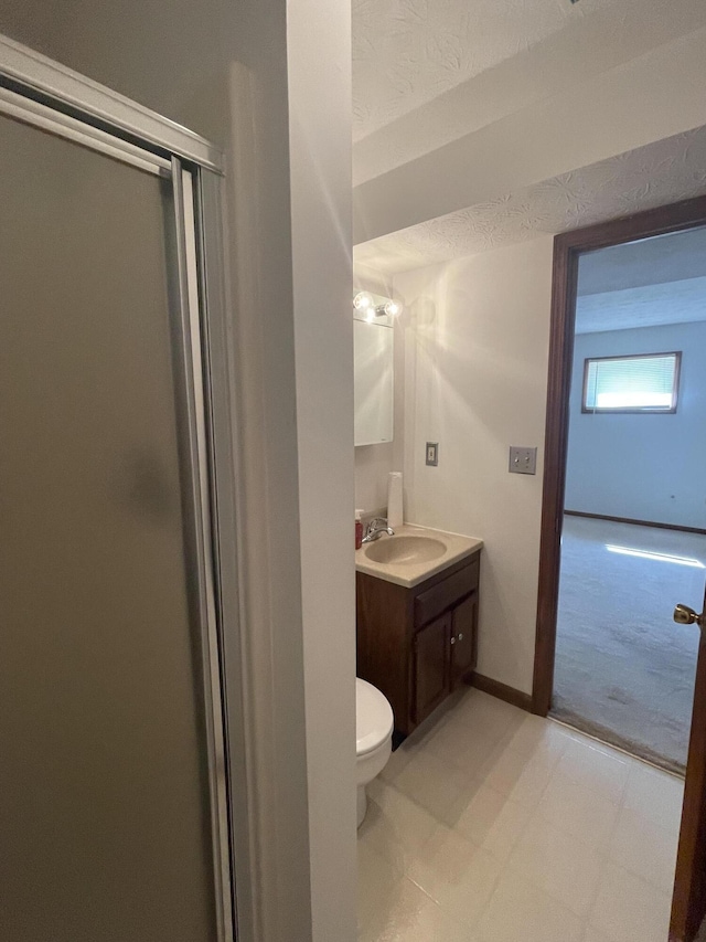 bathroom with a shower with door, vanity, and toilet