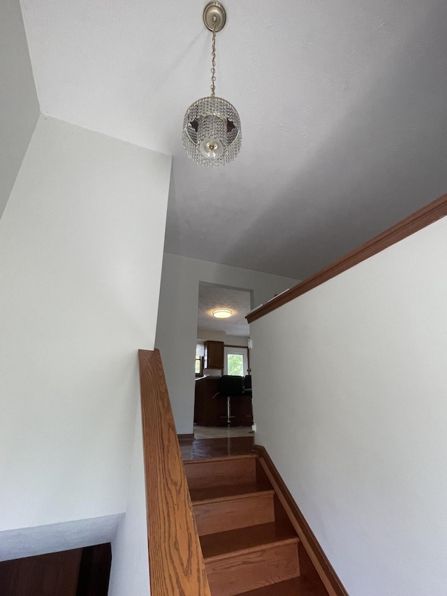 stairway featuring a notable chandelier