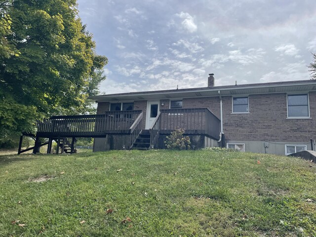 rear view of property with a wooden deck and a yard