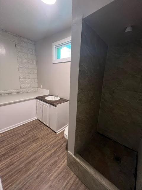 bathroom featuring a shower, wood-type flooring, vanity, and toilet