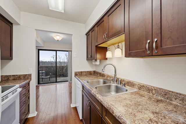 kitchen featuring dark brown cabinetry, light stone countertops, sink, dark hardwood / wood-style flooring, and white appliances