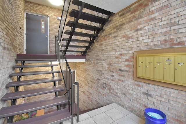 stairway featuring tile patterned floors, mail boxes, and brick wall