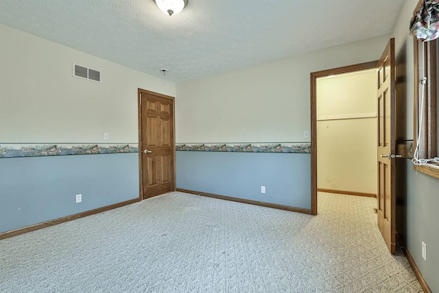 spare room featuring light carpet and a textured ceiling