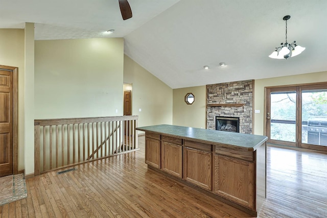 kitchen featuring pendant lighting, lofted ceiling, light hardwood / wood-style floors, a fireplace, and a kitchen island