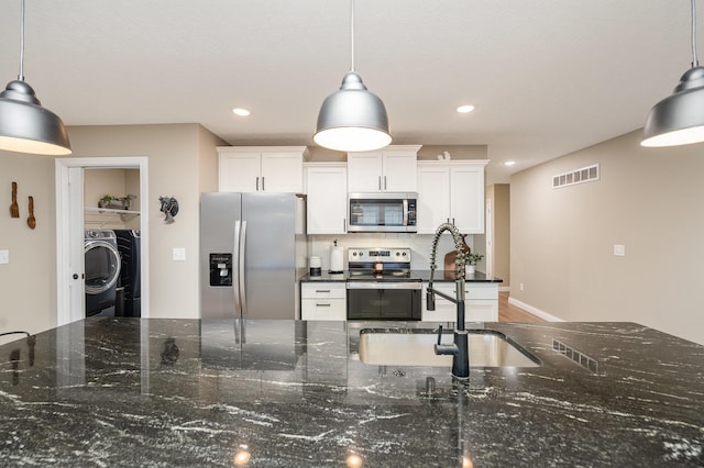 kitchen featuring hanging light fixtures, stainless steel appliances, tasteful backsplash, dark stone counters, and white cabinets