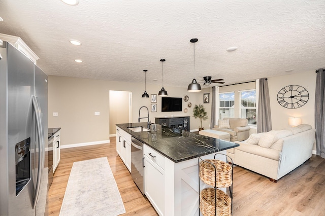 kitchen featuring white cabinetry, sink, decorative light fixtures, a kitchen island with sink, and appliances with stainless steel finishes