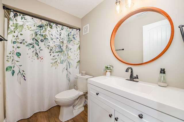 bathroom featuring toilet, vanity, a textured ceiling, and hardwood / wood-style flooring