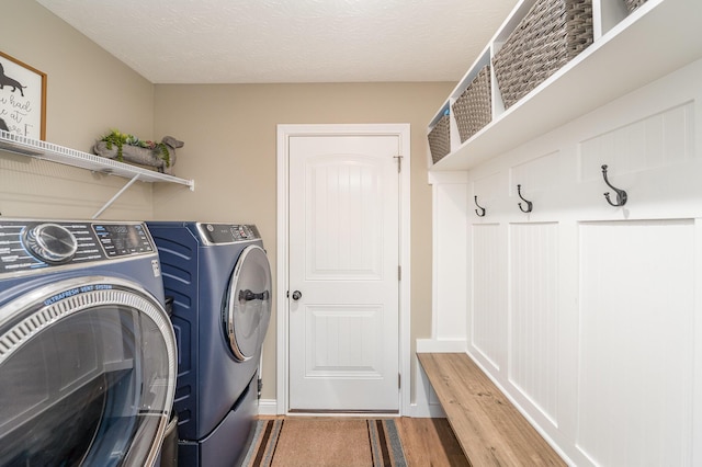 laundry room featuring hardwood / wood-style flooring, separate washer and dryer, and a textured ceiling