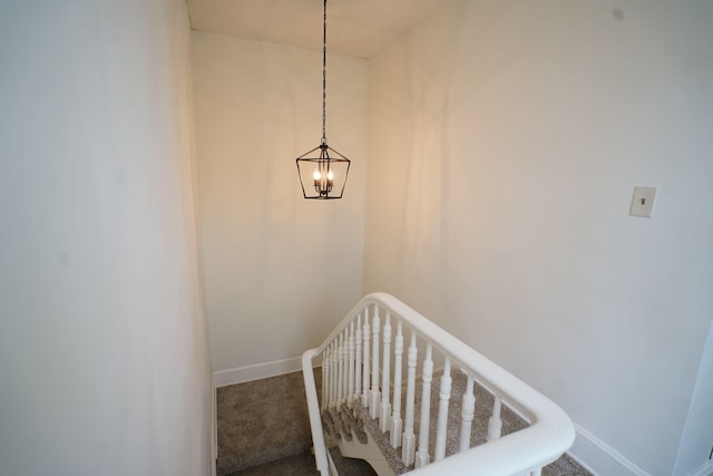 staircase featuring carpet flooring and a notable chandelier