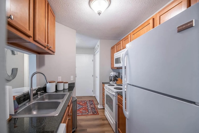 kitchen with a textured ceiling, sink, dark hardwood / wood-style floors, and white appliances