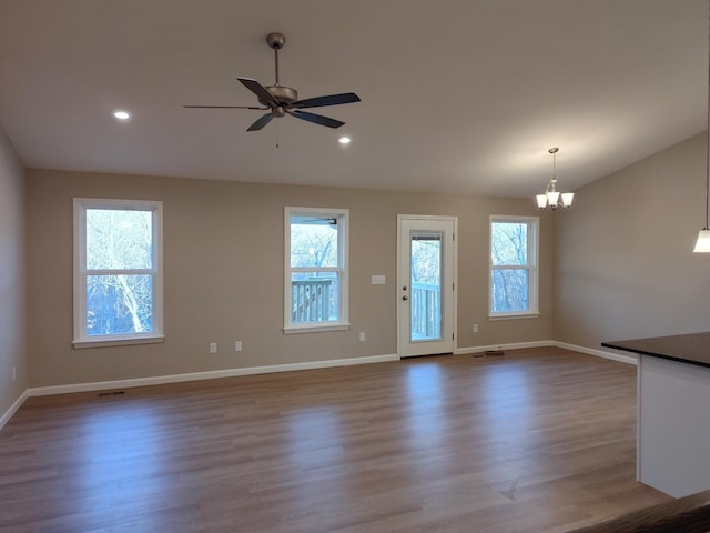 interior space with recessed lighting, baseboards, lofted ceiling, wood finished floors, and ceiling fan with notable chandelier