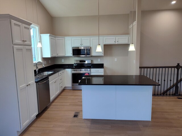 kitchen featuring white cabinetry, stainless steel appliances, a sink, and a center island