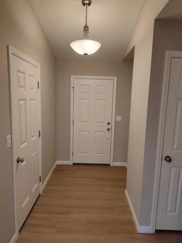 corridor featuring light wood finished floors and baseboards