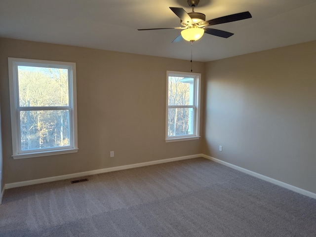 carpeted spare room with a ceiling fan, visible vents, and baseboards