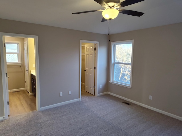 unfurnished bedroom featuring light carpet, a walk in closet, visible vents, and baseboards