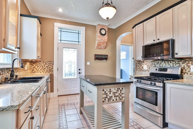 kitchen featuring stainless steel appliances, a center island, light stone countertops, and sink