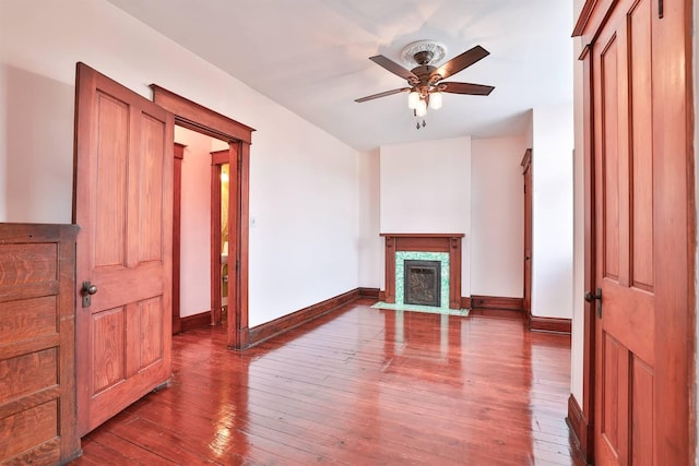 living room with a high end fireplace, wood-type flooring, and ceiling fan