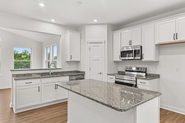6566 Cannondale Dr, Burlington, KY 41005 - kitchen with appliances with stainless steel finishes, a sink, wood finished floors, white cabinets, and a peninsula