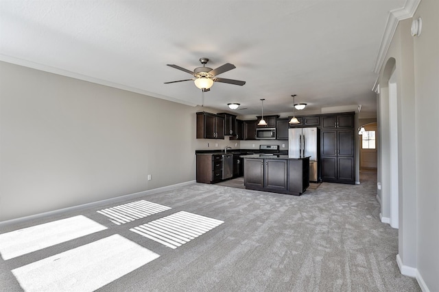 kitchen featuring appliances with stainless steel finishes, hanging light fixtures, ornamental molding, a center island, and ceiling fan