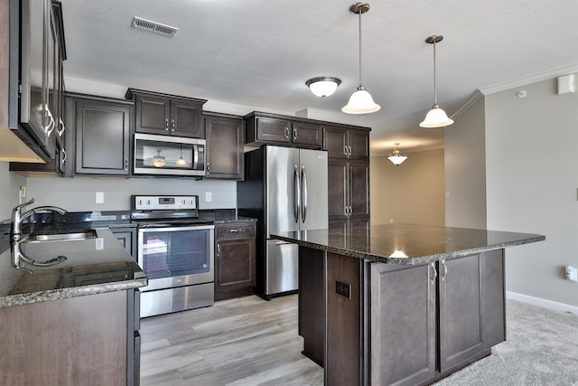 kitchen featuring sink, a center island, hanging light fixtures, dark stone counters, and stainless steel appliances