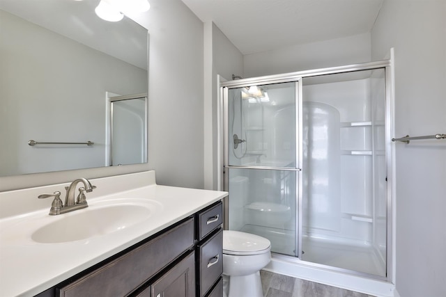 bathroom with hardwood / wood-style flooring, vanity, an enclosed shower, and toilet