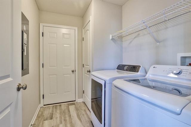 clothes washing area with washing machine and clothes dryer and light wood-type flooring