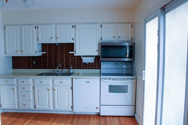 kitchen featuring sink, tasteful backsplash, white appliances, white cabinets, and light wood-type flooring