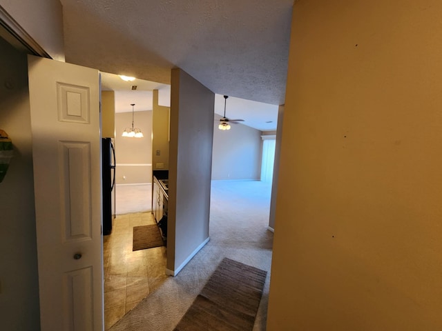 corridor featuring a chandelier, a textured ceiling, and light colored carpet