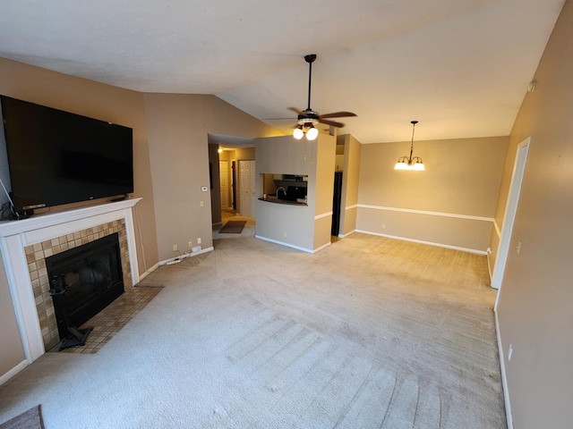 unfurnished living room with a tiled fireplace, light carpet, ceiling fan with notable chandelier, and lofted ceiling