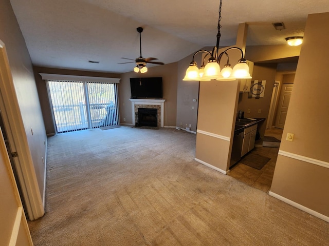 unfurnished living room with a tile fireplace, ceiling fan with notable chandelier, light colored carpet, and lofted ceiling