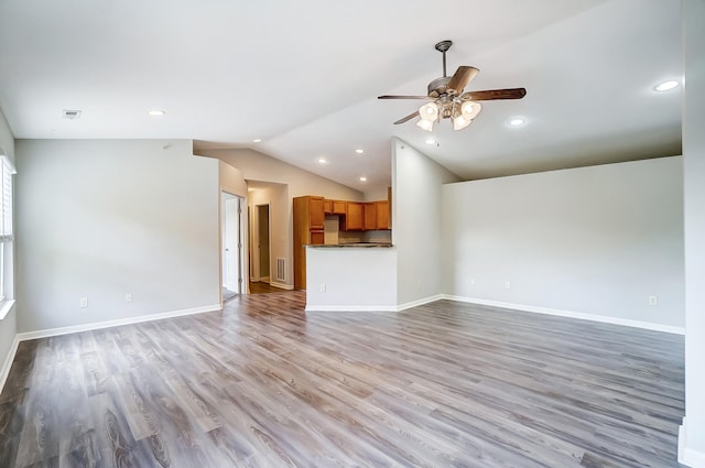 unfurnished living room with ceiling fan, vaulted ceiling, and light wood-type flooring