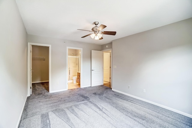 unfurnished bedroom featuring ensuite bath, ceiling fan, a spacious closet, carpet floors, and a closet