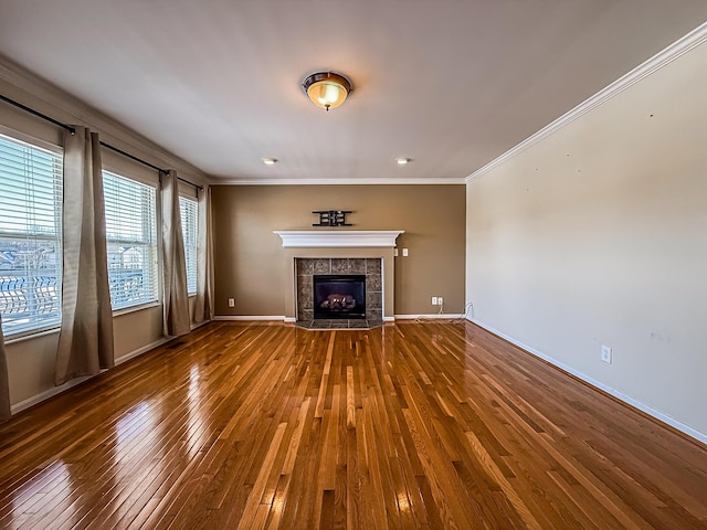 unfurnished living room with a tile fireplace, hardwood / wood-style floors, and crown molding