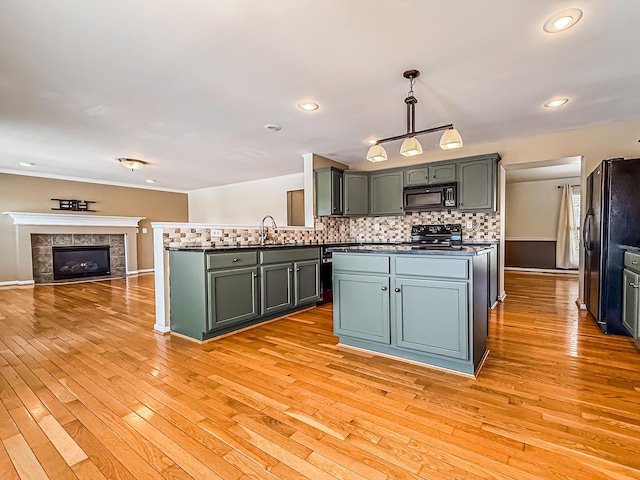 kitchen featuring black appliances, tasteful backsplash, sink, light hardwood / wood-style flooring, and pendant lighting