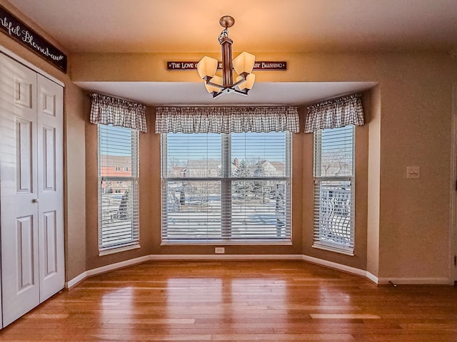 unfurnished dining area featuring hardwood / wood-style flooring, plenty of natural light, and a chandelier