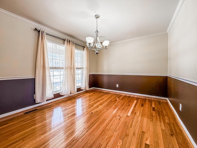 unfurnished room with hardwood / wood-style floors, crown molding, and a notable chandelier