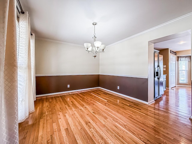 unfurnished dining area featuring crown molding, wood-type flooring, and a notable chandelier