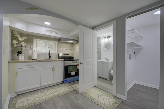 kitchen featuring light hardwood / wood-style flooring, stainless steel stove, white cabinetry, and sink